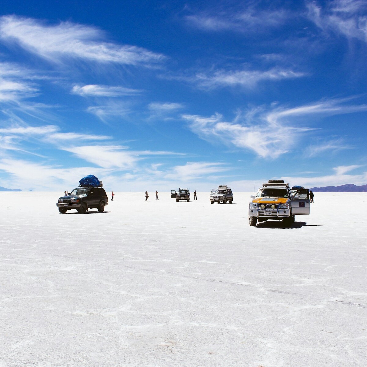 sports utility vehicles on desert under cloudy blue sky during daytime