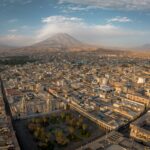 A panoramic view of a city with a mountain in the background
