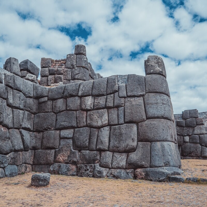 a large stone structure sitting on top of a dry grass field