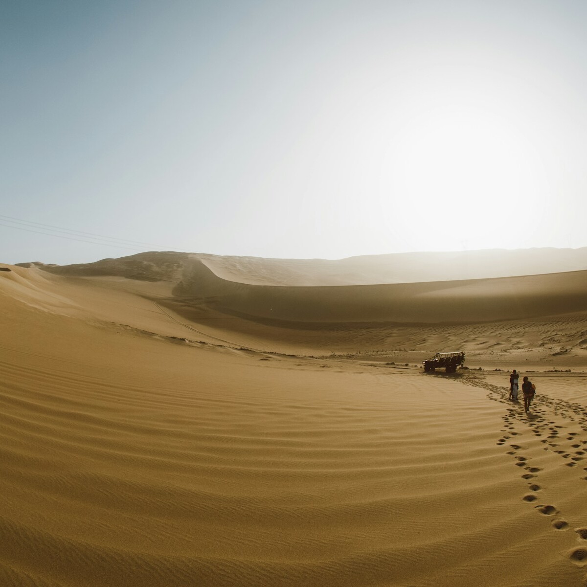 a couple of people walking across a desert