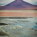 brown and white mountain near body of water during daytime
