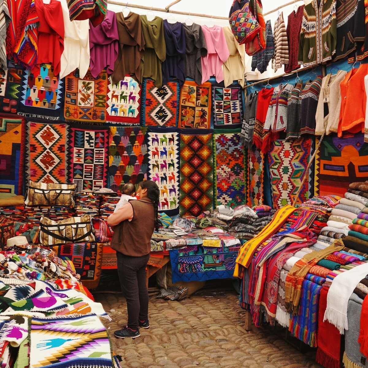 woman in store with display of assorted shirts and textiles