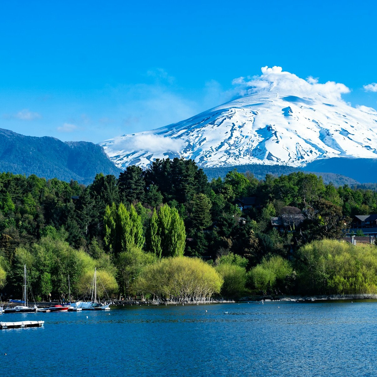 a lake with boats and a mountain in the background